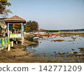 Wooden gazebo and fishing boat on low tide shore 142771209