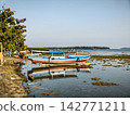 Wooden fishing boat resting on shallow sea shore 142771211