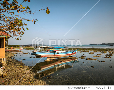 Traditional fishing boat stranded on low tide coast Traditional fishing boat stranded on low tide coast 142771215