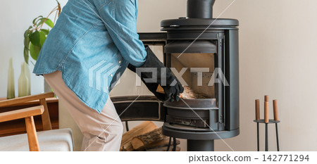 一位老人正在安全使用燃木爐。冬季安全措施，預防火災和一氧化碳中毒。 142771294
