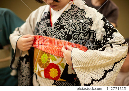 A child trying on a kimono for their coming-of-age ceremony in a Japanese-style room. A child trying on a kimono for their coming-of-age ceremony in a Japanese-style room. 142771815