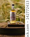 July 11, 2026, Minsk, Belarus - Farmer whiskey bottle on wooden table in field with wheat at golden hour 142772413