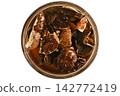 Dried mushrooms soaking in water in glass jar on brown background 142772419