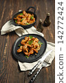 Pork stir fry served in black plates with side dishes and seasoning 142772424
