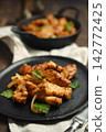 Pork stir fry cooked in a skillet with herbs on a plate 142772425