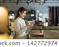A woman using a smartphone in a cafe 142772974