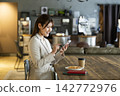A woman using a smartphone in a cafe 142772976