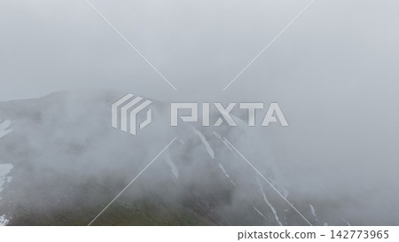 Foggy mountain landscape with snow-capped peaks and low visibility Foggy mountain landscape with snow-capped peaks and low visibility 142773965