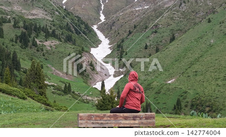 Person sitting on bench overlooking snow-capped mountains and valley Person sitting on bench overlooking snow-capped mountains and valley 142774004
