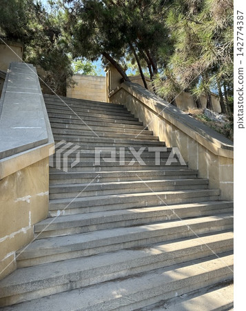 Wide concrete staircase leading through a green tree lined park pathway in summer. Stairs in the park. Wide concrete staircase leading through a green tree lined park pathway in summer. Stairs in the park. 142774387
