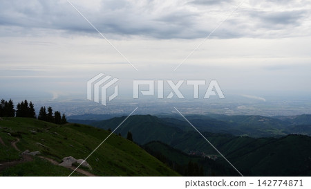 Scenic mountain view overlooking valley and cityscape under cloudy sky Scenic mountain view overlooking valley and cityscape under cloudy sky 142774871