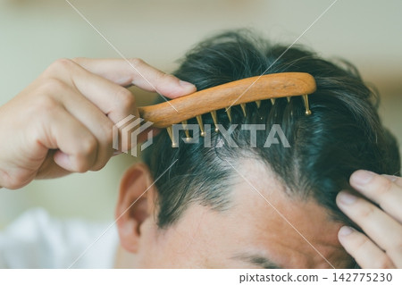Hair care time: Scalp massage with a comb-shaped gua sha tool. 142775230