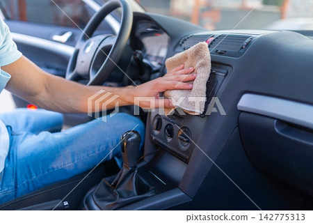 The driver cleans the interior of the vehicle while sitting inside the cabin The driver cleans the interior of the vehicle while sitting inside the cabin 142775313