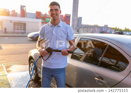 Man holding high pressure washer gun near silver car Man holding high pressure washer gun near silver car 142775315