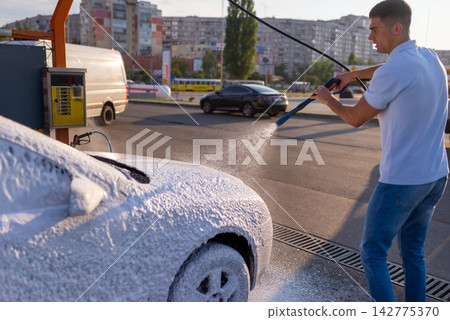 Man spraying water on silver car at self service car wash Man spraying water on silver car at self service car wash 142775370