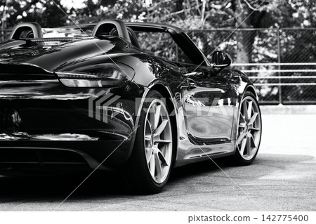 一輛黑色的保時捷981 Boxster Spyder跑車,像鏡子一樣映照著周圍的景色。 一輛黑色的保時捷981 Boxster Spyder跑車,像鏡子一樣映照著周圍的景色。 142775400