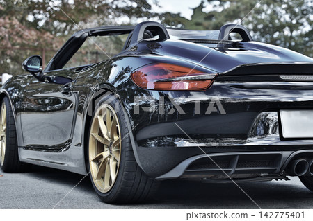 一輛黑色的保時捷981 Boxster Spyder跑車,像鏡子一樣映照著周圍的景色。 一輛黑色的保時捷981 Boxster Spyder跑車,像鏡子一樣映照著周圍的景色。 142775401