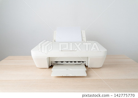 Minimal white printer sits on a light wooden desk in a clean home office setting, paper loaded in the tray and ready for printing documents, paperwork, and everyday use. Minimal white printer sits on a light wooden desk in a clean home office setting, paper loaded in the tray and ready for printing documents, paperwork, and everyday use. 142775770