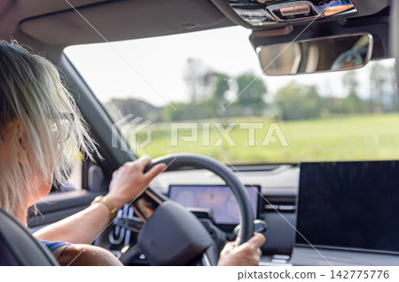 Rear view of a woman driving a modern car. Rear view of a woman driving a modern car. 142775776