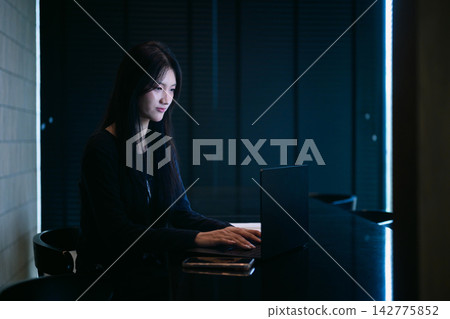 Young Woman Working Late on Laptop in Dark Modern Office with Blue Neon Light Young Woman Working Late on Laptop in Dark Modern Office with Blue Neon Light 142775852