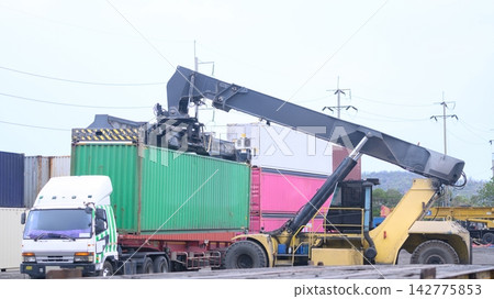 Green container lifted by heavy crane at port 142775853