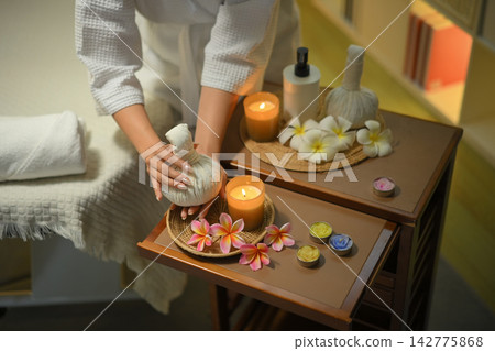Spa setup with herbal compress candles flowers and relaxing wellness mood 142775868