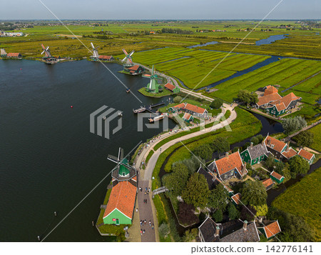 High angle wide horizontal aerial drone photograph of Zaanse Schans historic windmills, river Zaan, green wooden houses, polder canals, and walking paths in Zaandam, North Holland, Netherlands High angle wide horizontal aerial drone photograph of Zaanse Schans historic windmills, river Zaan, green wooden houses, polder canals, and walking paths in Zaandam, North Holland, Netherlands 142776141