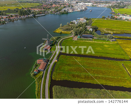 High angle wide horizontal aerial drone photograph of Zaanse Schans historic windmills, river Zaan, polder drainage canals, and industrial Zaandijk in Zaandam, North Holland, Netherlands on day High angle wide horizontal aerial drone photograph of Zaanse Schans historic windmills, river Zaan, polder drainage canals, and industrial Zaandijk in Zaandam, North Holland, Netherlands on day 142776144