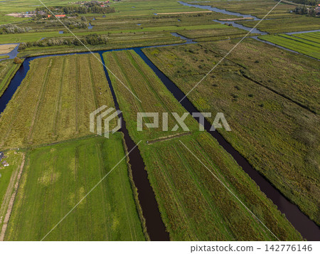 High angle wide horizontal aerial drone photograph of polder land reclamation geometry, linear drainage canals, peat meadows, and pasture fields in Zaandam, North Holland, Netherlands on day 142776146