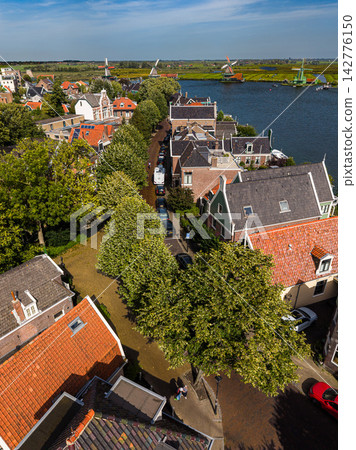 High angle vertical aerial drone photograph of Lagedijk street, historic brick houses, trees, Zaan river, and Zaanse Schans windmills in Zaandijk, North Holland, Netherlands on sunny day High angle vertical aerial drone photograph of Lagedijk street, historic brick houses, trees, Zaan river, and Zaanse Schans windmills in Zaandijk, North Holland, Netherlands on sunny day 142776150