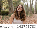 Young woman smiling looking up in autumn forest 142776783