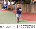 Toddler boy playing with ball in park 142776784
