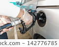 Person refueling car at gas station wearing gloves for hygiene 142776785