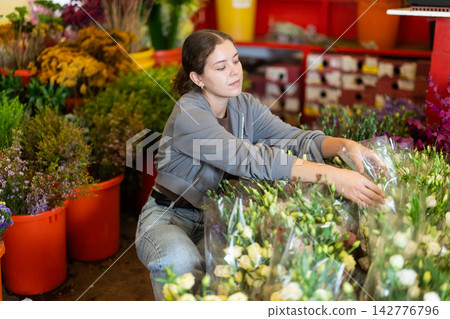 Female customer chooses a bouquet of roses in flower shop Female customer chooses a bouquet of roses in flower shop 142776796