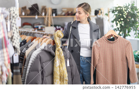 Adult woman chooses warm dress in clothing store 142776955