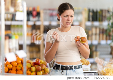 Young woman with rotten apples in grocery store 142776979