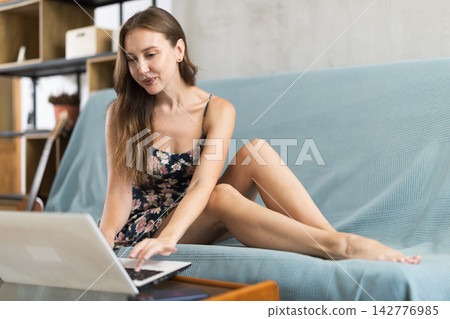 Woman freelancer working on laptop in living room and solving work issues Woman freelancer working on laptop in living room and solving work issues 142776985
