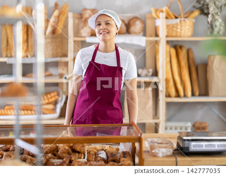 Uniformed saleswoman stands behind the counter Uniformed saleswoman stands behind the counter 142777035