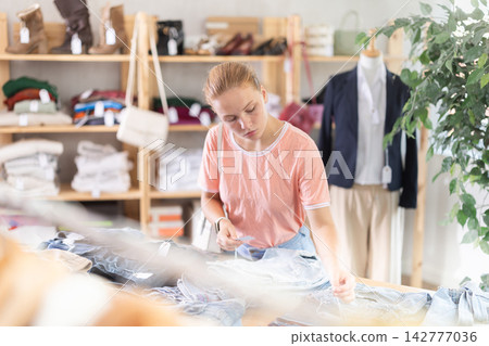 Search and selection of new jeans or shorts in a clothing store for young girl Search and selection of new jeans or shorts in a clothing store for young girl 142777036