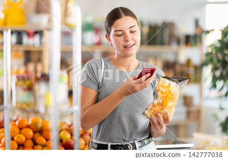 Young woman scanning qr code for snack mix Young woman scanning qr code for snack mix 142777038