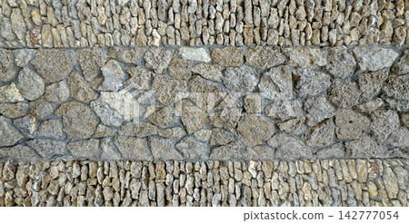 Rustic limestone rock wall built with stacked natural stones and varied rough masonry courses Rustic limestone rock wall built with stacked natural stones and varied rough masonry courses 142777054
