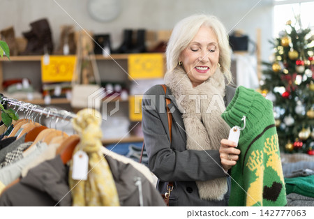 Elderly woman choosing a reindeer sweater Elderly woman choosing a reindeer sweater 142777063