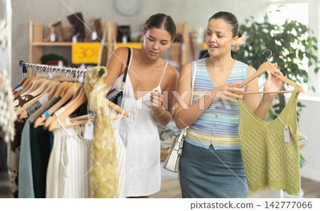 Near rack, female friends buy summer clothes, choose some items 142777066