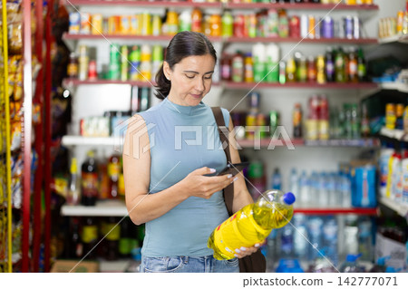 Female buyer scans barcode code on soft drinks in grocery store 142777071