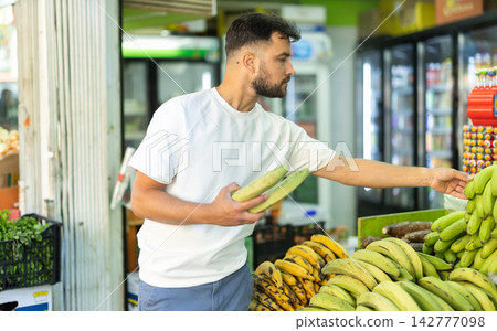 Man customer in supermarket search, choose cooking banana goods Man customer in supermarket search, choose cooking banana goods 142777098