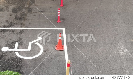 Handicap accessible parking spot with orange traffic cones on asphalt pavement 142777180
