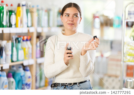 Young woman client sniffs fragrance of perfume, chooses scent spray with pleasant smell Young woman client sniffs fragrance of perfume, chooses scent spray with pleasant smell 142777291