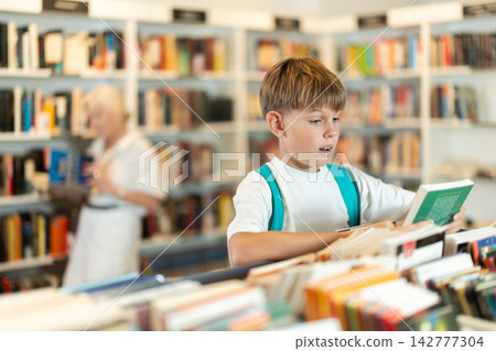 Teenage boy choosing book in bookstore Teenage boy choosing book in bookstore 142777304