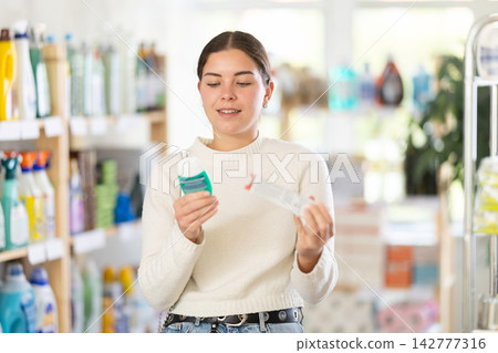 Girl housewife in household store examines goods, chooses oral hygiene products Girl housewife in household store examines goods, chooses oral hygiene products 142777316