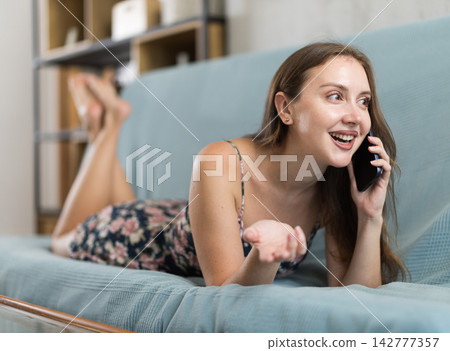 Brunette woman talking on the phone in the living room Brunette woman talking on the phone in the living room 142777357